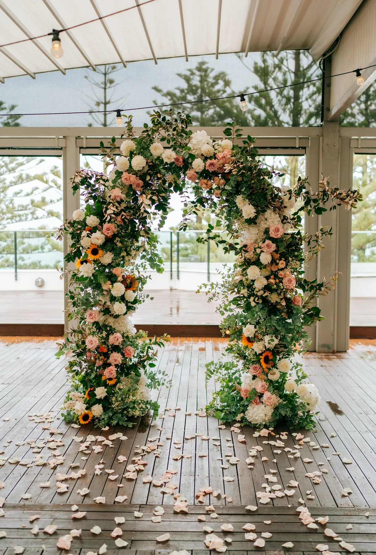 Floral wedding arch on a timber deck